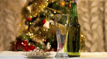 A bottle of beer on a table in front of a Christmas tree.