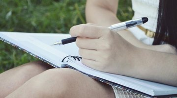 Close-up of student holding notebook and pen.