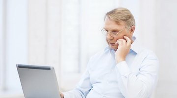 Older teaching typing at laptop