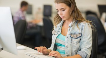 High school student typing on computer in library