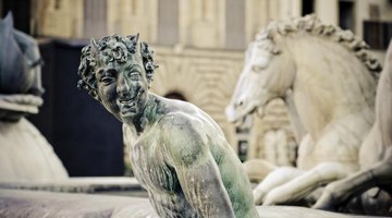 Statues of mythological characters in front of an ancient building in Greece.