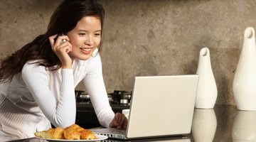 Woman making phone call while researching on laptop.