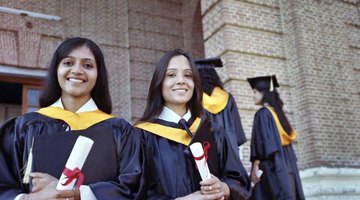 Smiling graduates holding their degrees in hand.