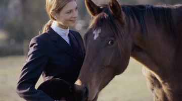 A young woman is standing next to her horse.