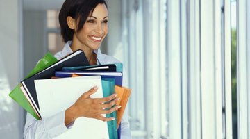Social worker holding stacks of portfolios and paperwork.