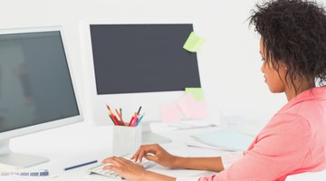 Web designer sitting in front of two desktops