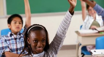 Students raising their hands in classroom.