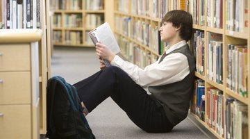 Teenage boy reading in the library.