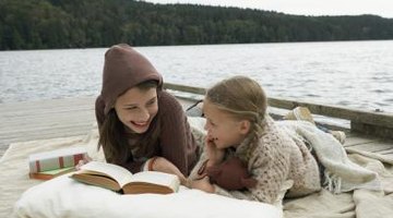 Two young girls are reading outside.