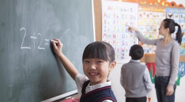 Student answering simple addition problem on chalkboard.