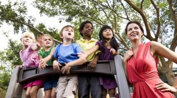 Smiling day care worker with students on playground